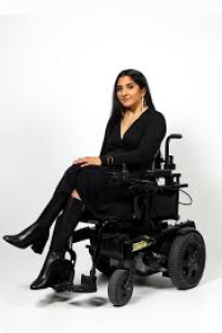 A woman in a wheelchair in a stylish IZ adaptive seated wrap dress in black.